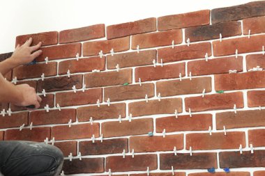 Profesyonel müteahhit duvara dekoratif tuğla yapıştırıyor, yakın plan. Döşeme kurulum süreci