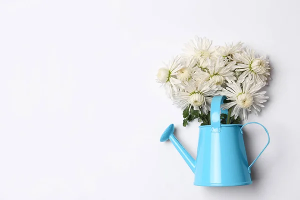 Watering can with beautiful flowers on white background, top view. Space for text