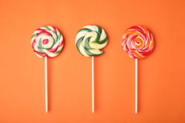 Turuncu arka planda renkli lolipoplar, düz yatış