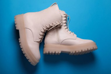 Açık mavi arka planda bir çift şık deri ayakkabı.