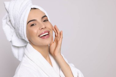 Açık gri arka planda havlusu olan bornozlu genç bir kadın, mesaj için yer var. Spa tedavisi