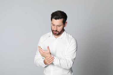 Hafif arka planda elinde acı çeken bir adam. Artrit belirtileri