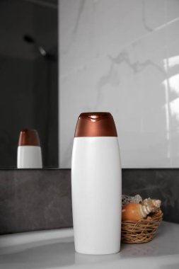 Bir şişe duş jeli ve lavaboda kabukları olan hasır sepet.