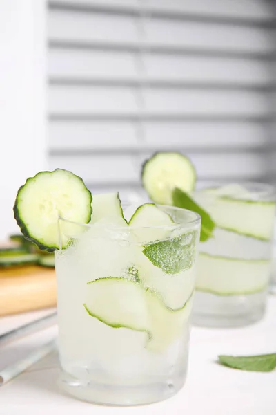 Tasty fresh cucumber water with mint on white wooden table