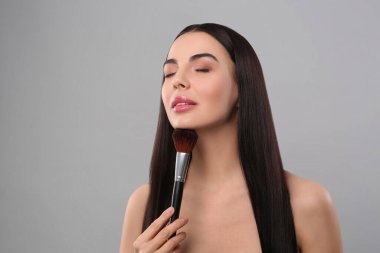 Açık gri arkaplanda makyaj fırçası olan güzel kadın, metin için boşluk
