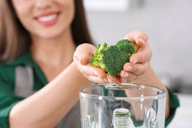 Smoothie için karıştırıcıya brokoli ekleyen kadın arka planda bulanık, yakın plan