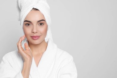 Açık gri arka planda havlusu olan bornozlu genç bir kadın, mesaj için yer var. Spa tedavisi