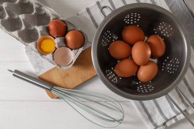 Kevgir, peçete ve çırpılmış taze çiğ tavuk yumurtaları beyaz ahşap masa, düz yatıyordu.