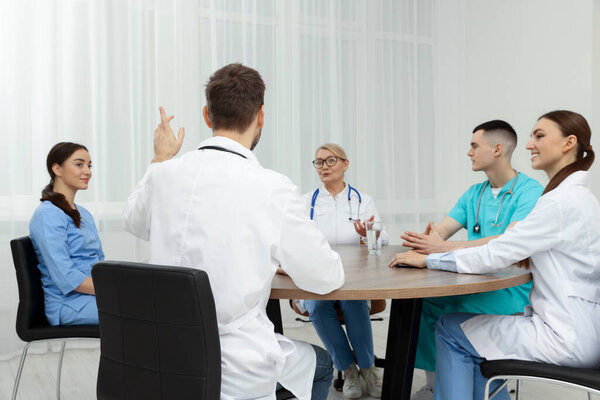 Medical conference. Team of doctors having discussion at wooden table in clinic