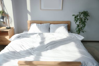 Yumuşak yastıkları ve battaniyesi olan büyük, rahat bir yatak.