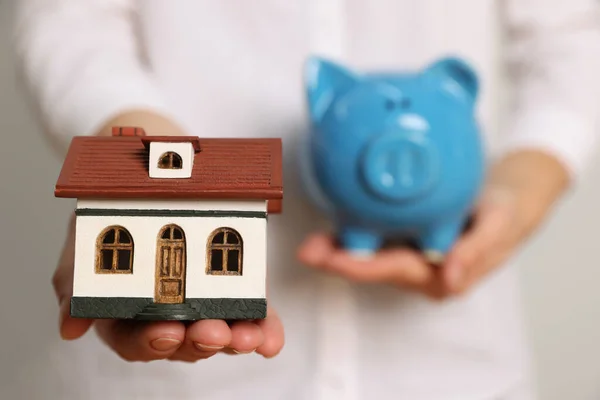 Woman Holding Piggy Bank Light Grey Background Focus Little House — Foto de Stock