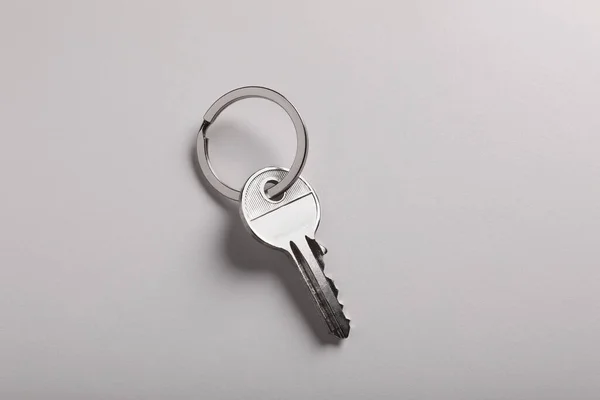 House key on light grey background, top view. Real estate agent services