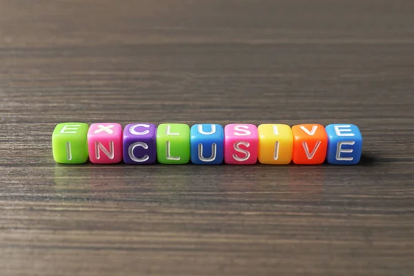 Colorful cubes with word Inclusive on wooden table