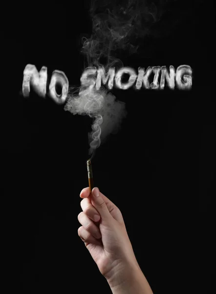 No Smoking. Woman holding cigarette on black background, closeup. Phrase of smoke