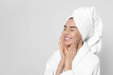 Açık gri arka planda havlusu olan bornozlu genç bir kadın, mesaj için yer var. Spa tedavisi