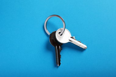 Evin anahtarları açık mavi arka planda, üst manzara. Emlakçılık hizmetleri