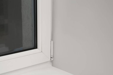 Beyaz duvarın yanındaki cam plastik pencere.