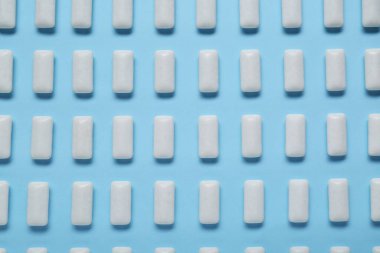 Açık mavi arkaplanda beyaz sakız çiğniyor.