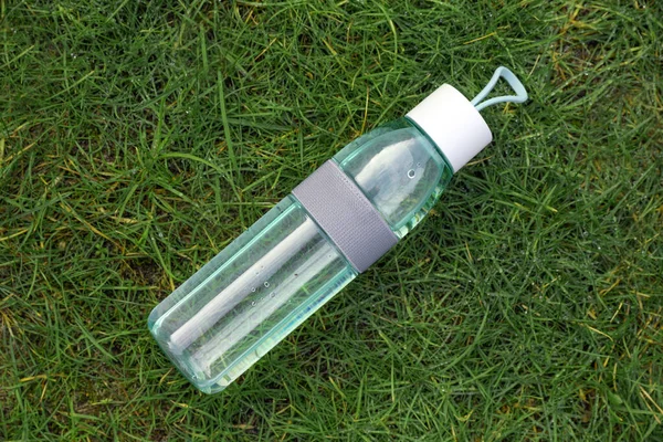 Bottle of water on green grass, top view. Morning exercise