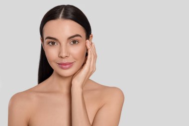 Açık gri arka planda çekici genç bir kadının portresi, yazı için boşluk. Spa tedavisi