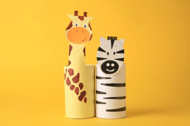 Oyuncak zürafa ve zebra sarı arka plandaki tuvalet kağıdı merkezlerinden yapılmış. Çocukların el yapımı fikirleri.