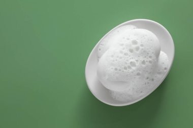 Sabun kalıplı tabak ve yeşil arka planda kabarık köpük, üst manzara. Metin için boşluk