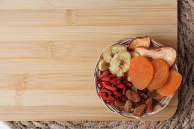 Tahta üzerinde farklı kurutulmuş meyveler olan sepet, üst manzara. Metin için boşluk
