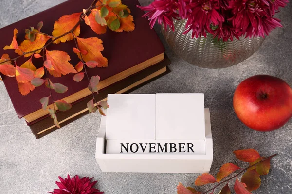 Thanksgiving day, holiday celebrated every fourth Thursday in November. Flat lay composition with wooden block calendar and autumn leaves on grey table
