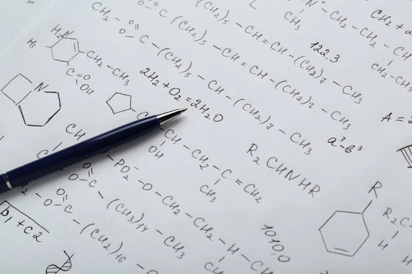 Sheet of paper with different chemical formulas and pen, closeup