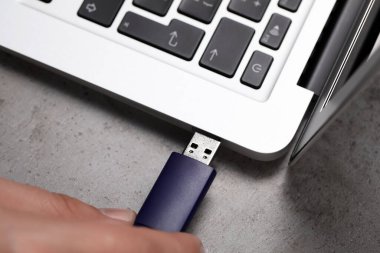 USB flash diski gri masadaki bilgisayara bağlayan adam.