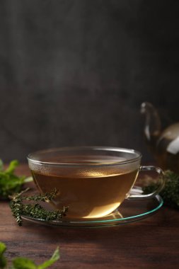 Bir fincan aromatik bitki çayı ve ahşap masada taze kekik.