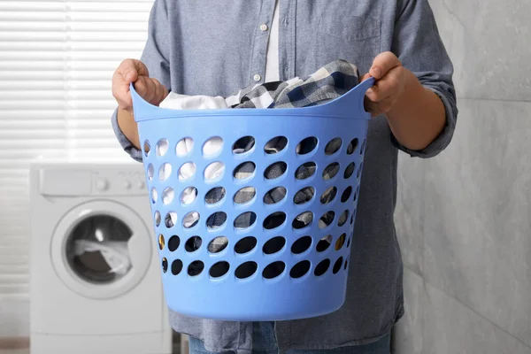 Man with basket full of laundry in bathroom, closeup