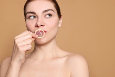 Bej arka planda prezervatif tutan kadın. Güvenli seks.