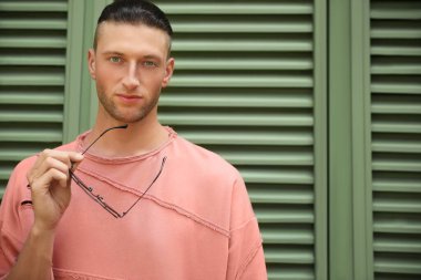 Panjurların yanında şık güneş gözlüklü yakışıklı genç adam, mesaj için yer var.