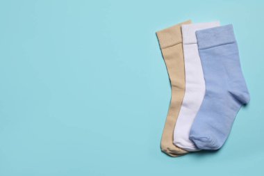 Açık mavi arka planda farklı çoraplar, düz yatış. Metin için boşluk