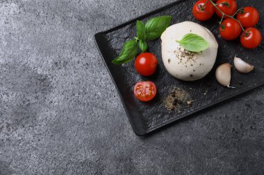 Açık gri desenli masa üzerinde domates ve fesleğen yapraklı lezzetli mozzarella. Metin için boşluk