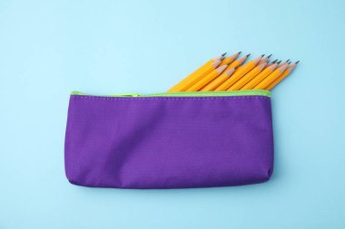 Açık mavi arkaplanda, kalem kutusunda birçok keskin kalem, üst görünüm