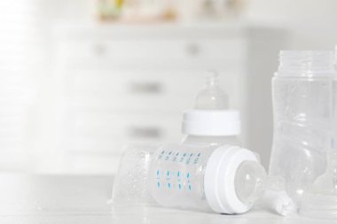 Beyaz masa içerisindeki sterilizasyondan sonra temiz bebek şişeleri ve meme uçları, yakın plan. Metin için boşluk