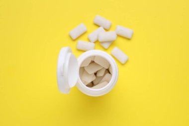 Sarı arka planda sakız çiğneyen kavanoz, düz uzan.