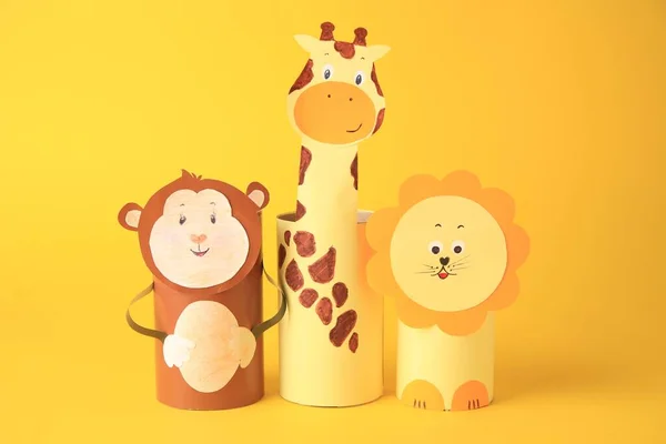Toy monkey, giraffe and lion made from toilet paper hubs on yellow background. Children\'s handmade ideas