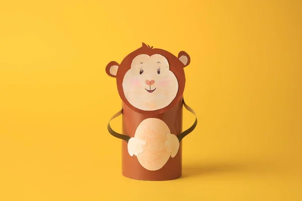 Toy monkey made from toilet paper hub on yellow background. Children\'s handmade ideas