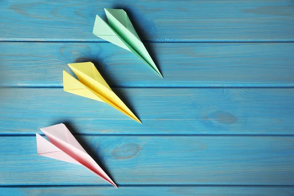 Handmade paper planes on light blue wooden table, flat lay. Space for text