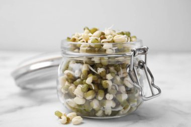 Yeşil fasulyeli cam kavanoz beyaz mermer masada, yakın plan.