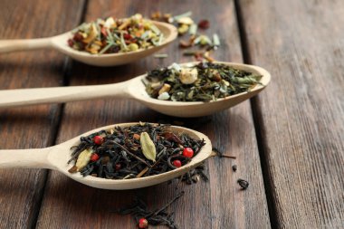 Tahta masada kurutulmuş çay yapraklı kaşıklar, yakın plan. Metin için boşluk