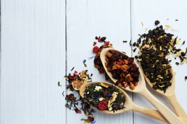 Kurutulmuş bitki çayı yapraklı kaşıklar ve beyaz ahşap masa üzerinde meyveler, düz bir yatak. Metin için boşluk