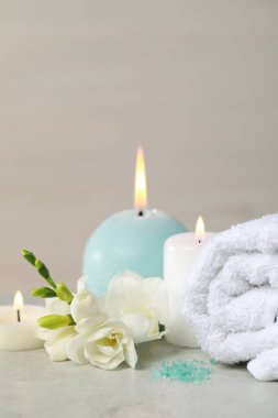 Güzel bir spa kompozisyonu yanan mum, sarılmış havlu ve beyaz masa üzerinde çiçekler