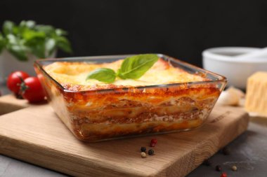 Gri masada pişirme kabında pişirilmiş lezzetli lazanya, yakın plan.