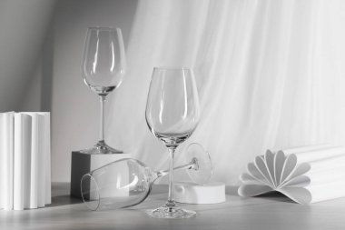 Boş şarap kadehleri, katlanmış kağıt dekorlar ve beyaz ahşap masada küp.