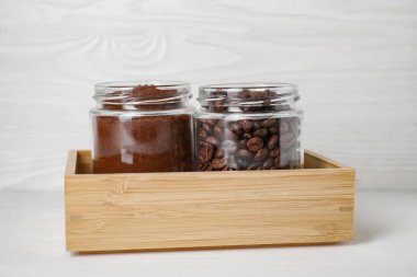 Kahveli kavanozlar ve beyaz ahşap masada fasulyeler.