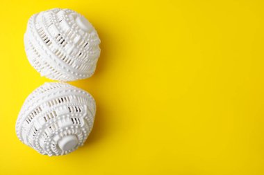 Sarı arka planda çamaşır kurutma makinası topları düz yerde. Metin için boşluk